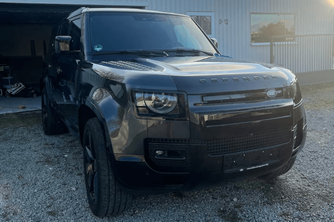 Frontansicht eines glänzenden, schwarzen Land Rover Defender. Der SUV wurde professionell außen gereinigt, wodurch sein robuster und luxuriöser Glanz hervorgehoben wird.